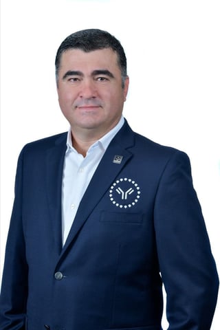 Professional headshot of a man in a dark blue blazer and light blue shirt against a white background